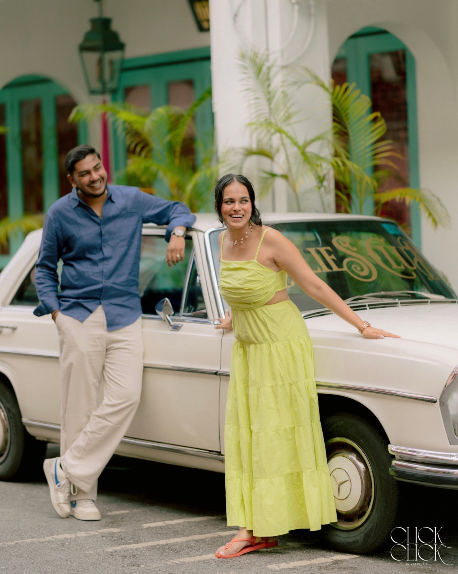 A couple sharing a playful moment beside a classic car